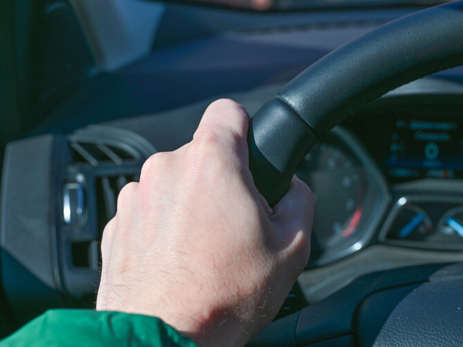 Hands hold the steering wheel of a car,