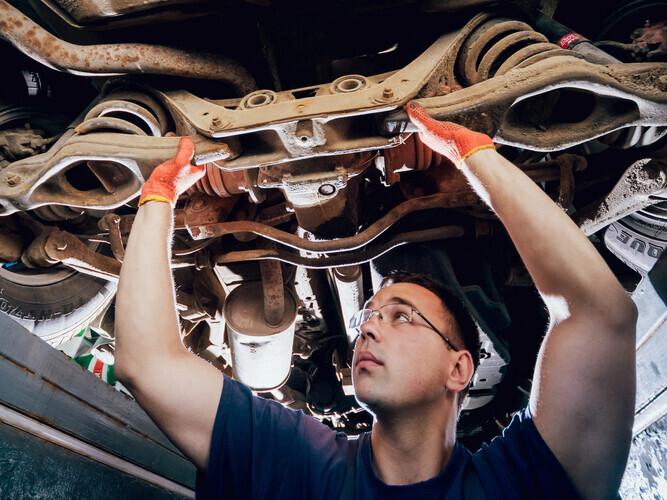 Car mechanic repair car suspension of lifted automobile