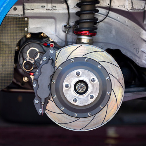 High performance brake caliper on a disc brakes with brake pads of a car. No tire.