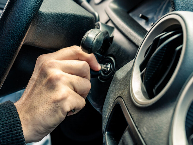A Hand holding car key for starting the car.
