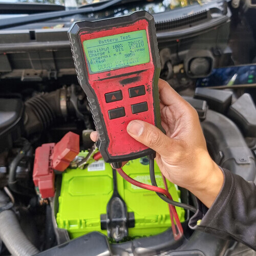 technician using a tool to diagnose a car battery