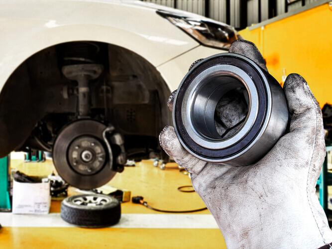 Mechanic holding wheel bearing in automotive workshop , Replacing the front wheel bearings of a car , Car maintenance concept
