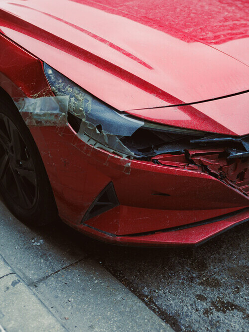 red car with a broken headlight