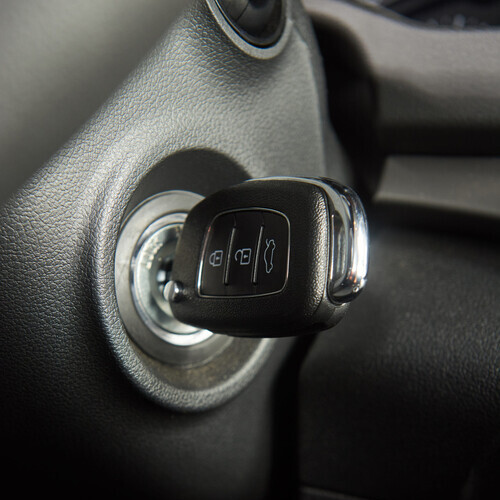 Close up of car key in keyhole for ignition. Macro of modern start car key vertical